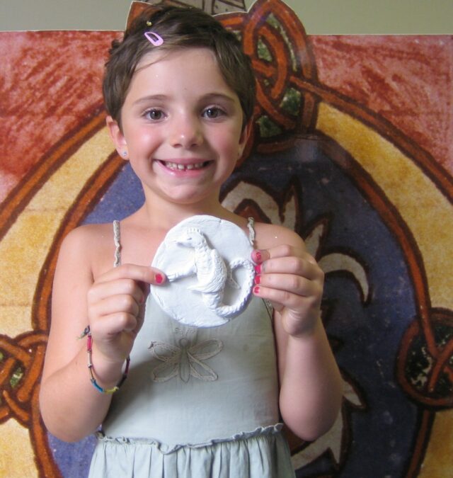 Une petit fille montre fièrement le dragon qu'elle vient de sculpter.